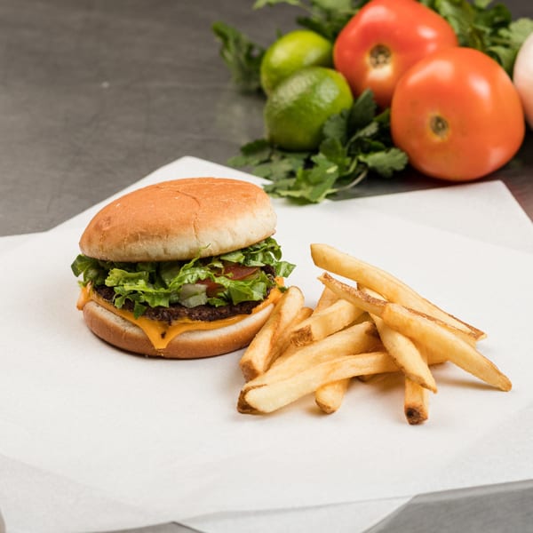 Cheeseburger with lettuce and tomato, served with a side of golden french fries.