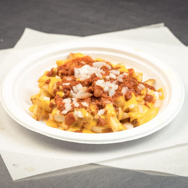 A white bowl of Go Burger chili cheese fries topped with diced white onions.